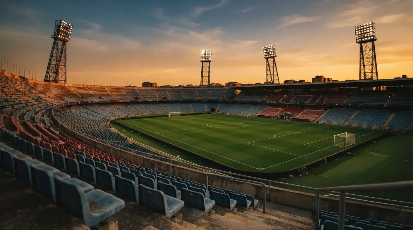 Un estadio de fútbol vacío con torres de iluminación al atardecer
