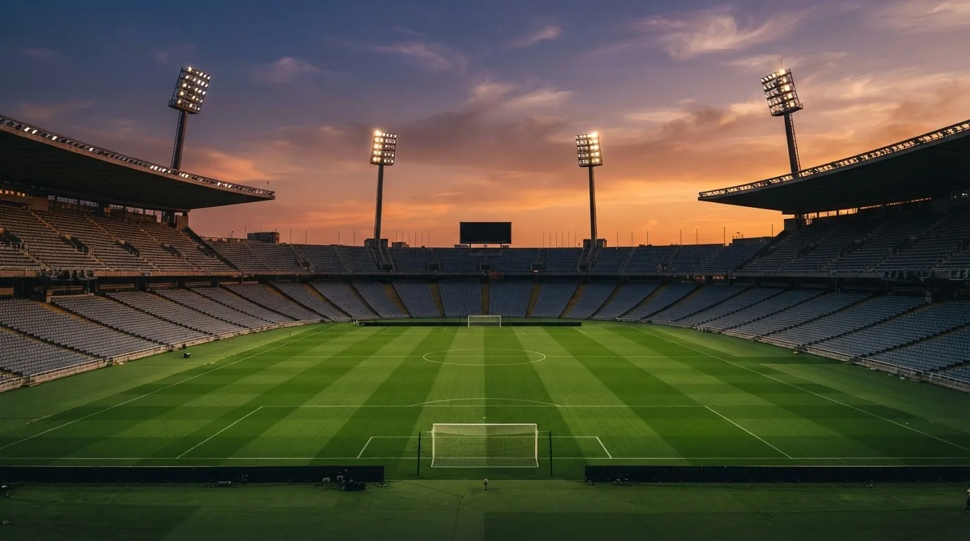 Un estadio de fútbol vacío con torres de iluminación al atardecer