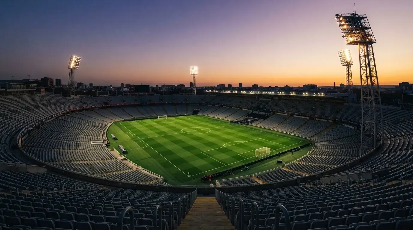 Un estadio de fútbol vacío con torres de iluminación al atardecer