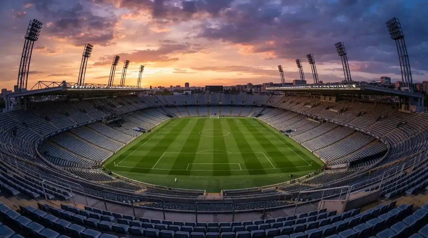 Un estadio de fútbol vacío con torres de iluminación al atardecer