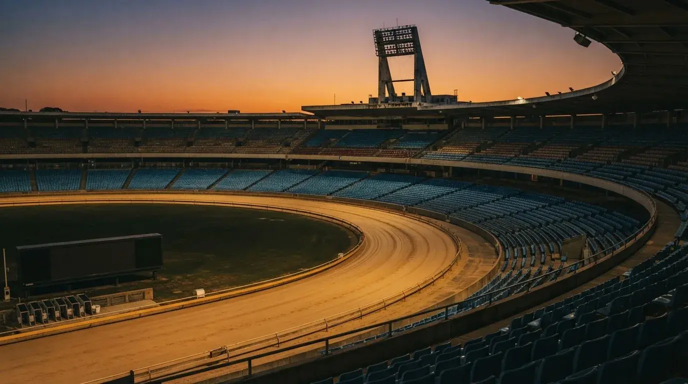 Un estadio de fútbol vacío con torres de iluminación al atardecer