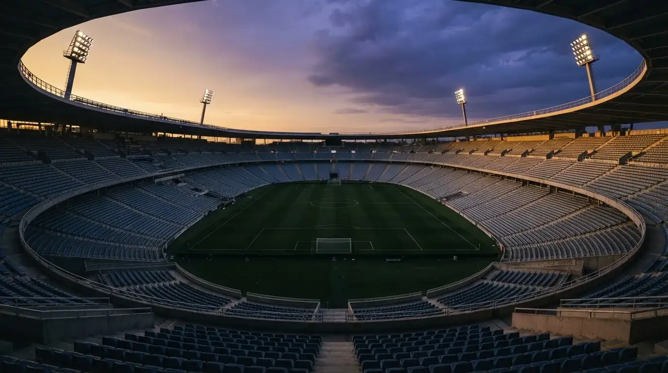 Un estadio de fútbol vacío con torres de iluminación al atardecer