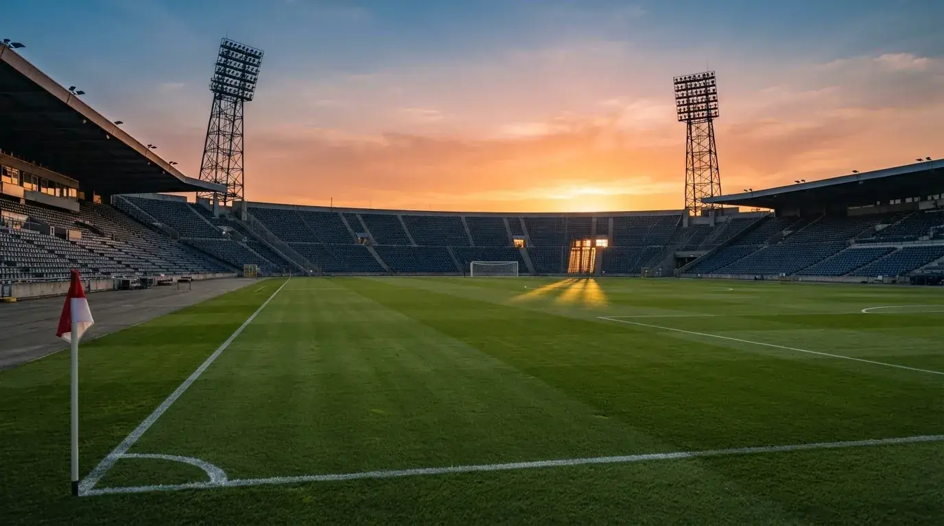 Un estadio de fútbol vacío con torres de iluminación al atardecer