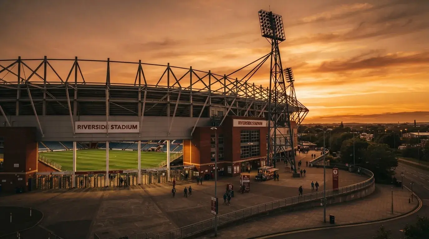 Un estadio de fútbol vacío con torres de iluminación al atardecer