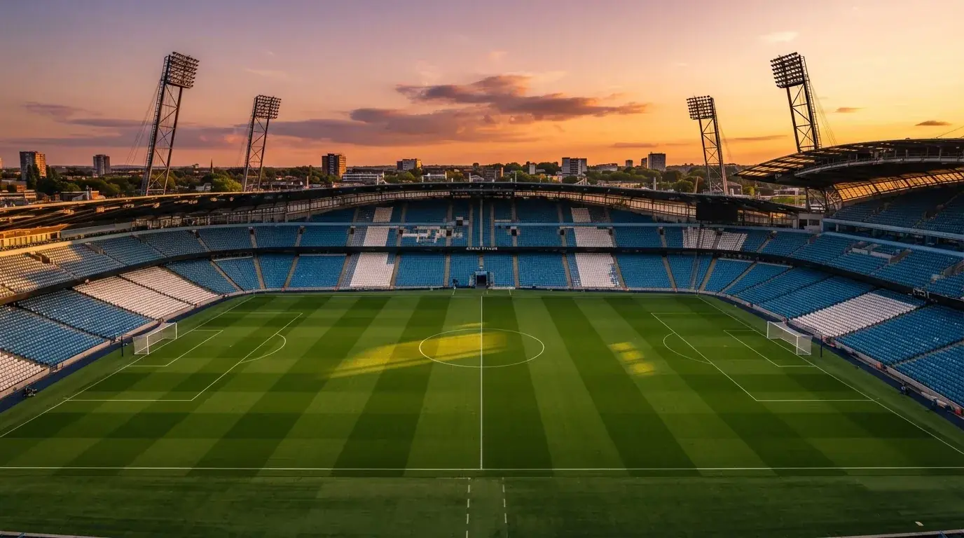 Un estadio de fútbol vacío con torres de iluminación al atardecer