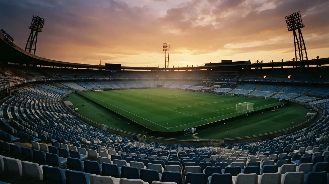 Un estadio de fútbol vacío con torres de iluminación al atardecer