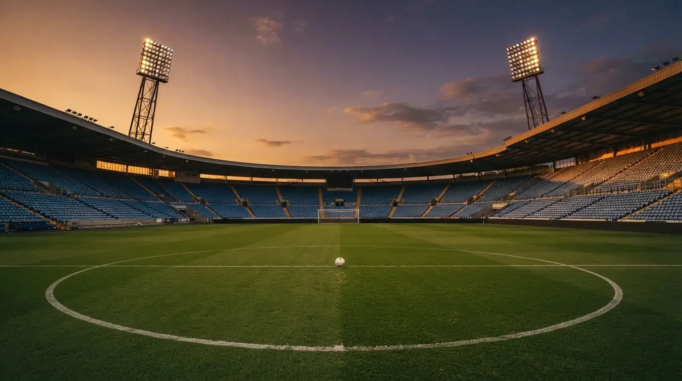 Un estadio de fútbol vacío con torres de iluminación al atardecer