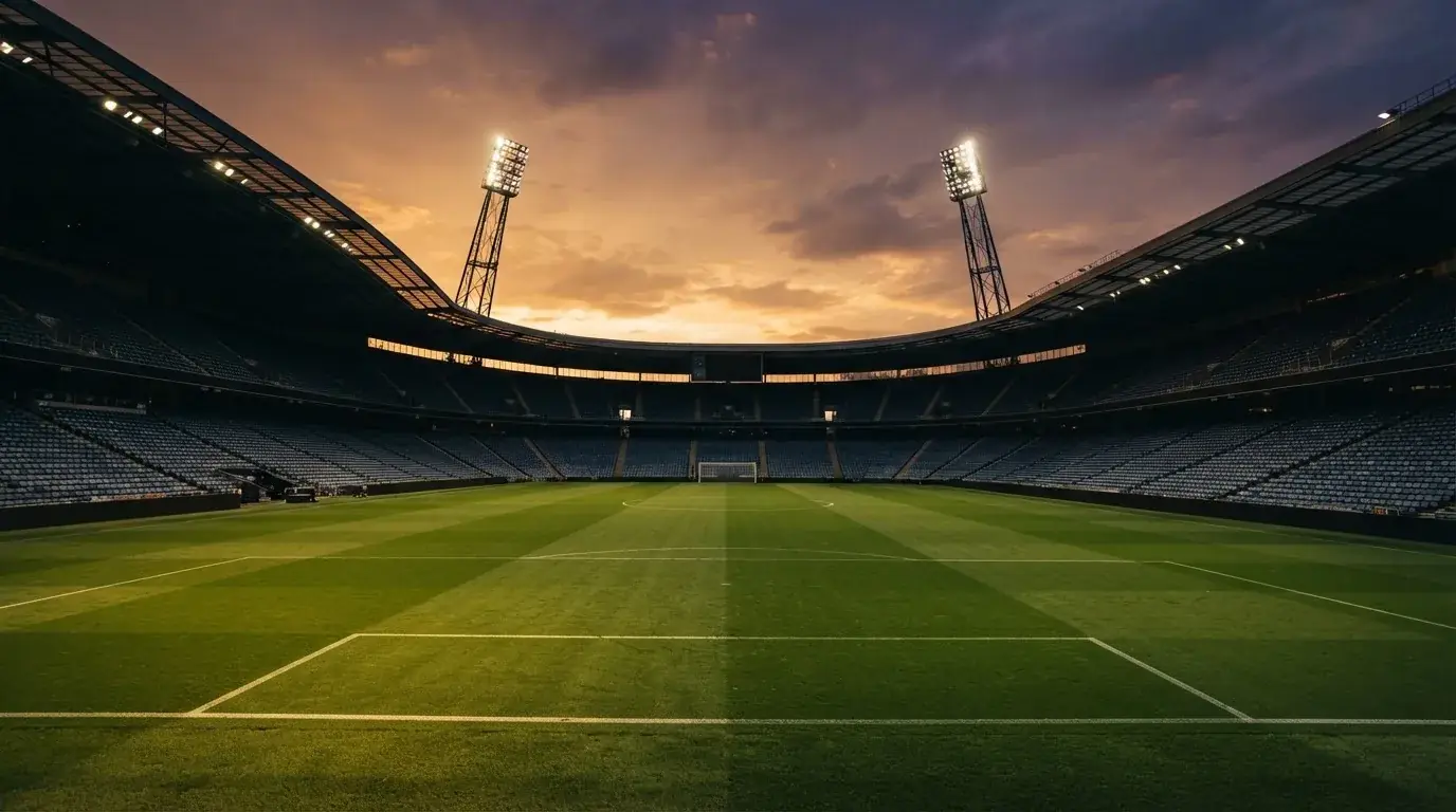 Un estadio de fútbol vacío con torres de iluminación al atardecer
