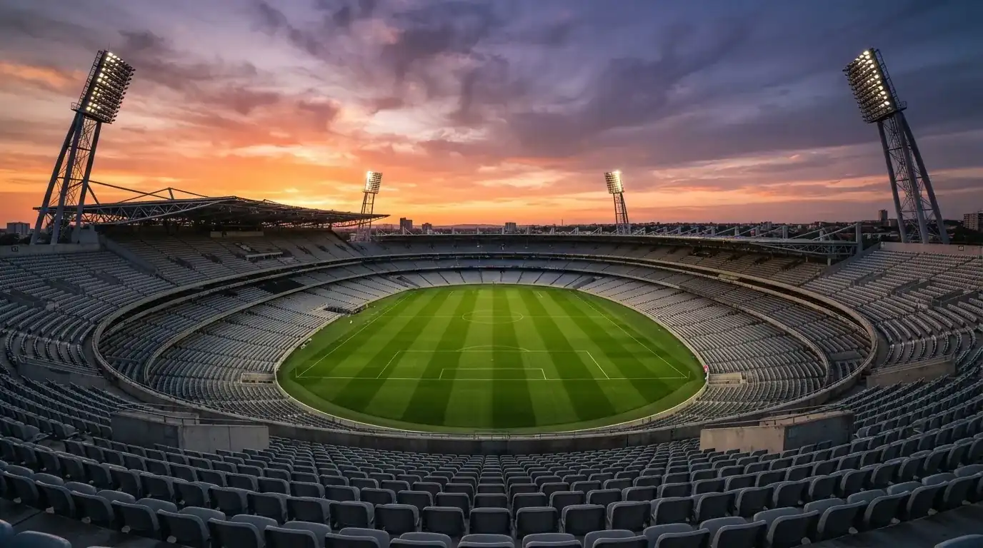 Un estadio de fútbol vacío con torres de iluminación al atardecer