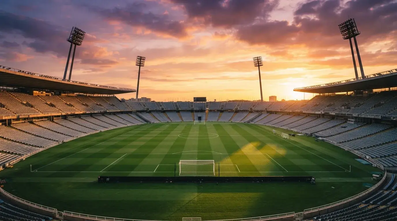 Un estadio de fútbol vacío con torres de iluminación al atardecer