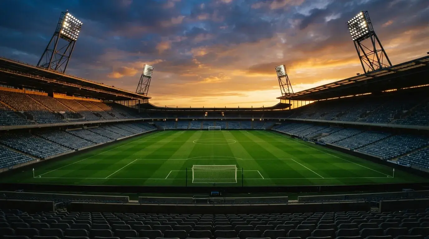 Un estadio de fútbol vacío con torres de iluminación al atardecer