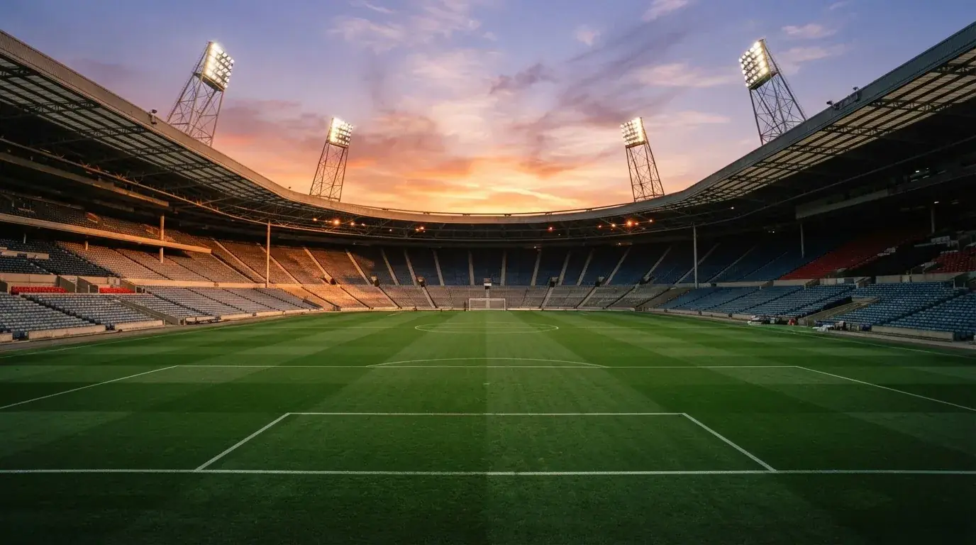 Un estadio de fútbol vacío con torres de iluminación al atardecer