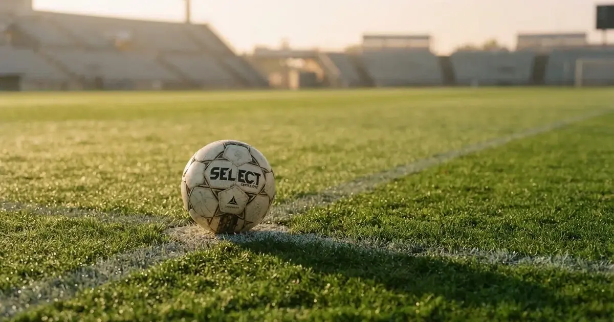 Un balón en el punto central de un campo de césped a la luz de la mañana