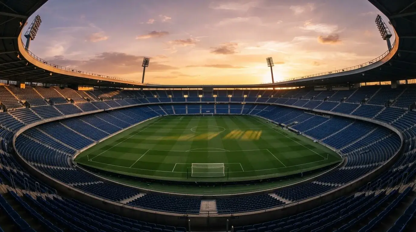 Un estadio de fútbol vacío con torres de iluminación al atardecer
