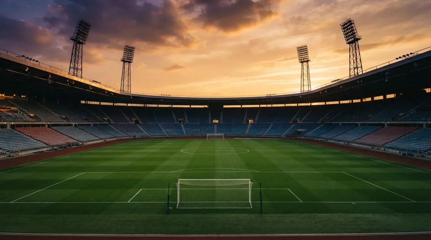 Un estadio de fútbol vacío con torres de iluminación al atardecer