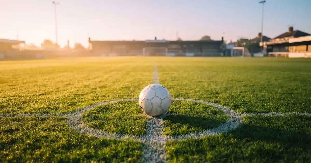 Un balón en el punto central de un campo de césped a la luz de la mañana